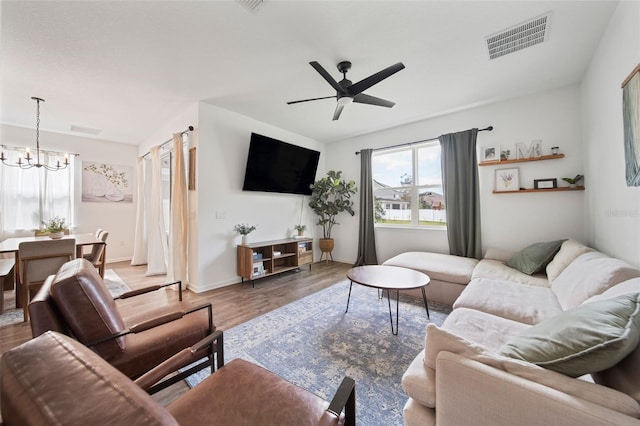 living room with baseboards, visible vents, wood finished floors, and ceiling fan with notable chandelier