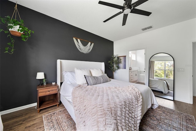 bedroom featuring dark wood finished floors, visible vents, an accent wall, connected bathroom, and baseboards