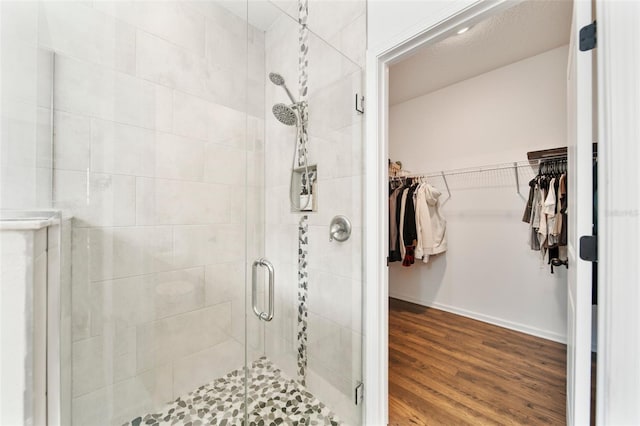 full bath with a spacious closet, wood finished floors, and a shower stall