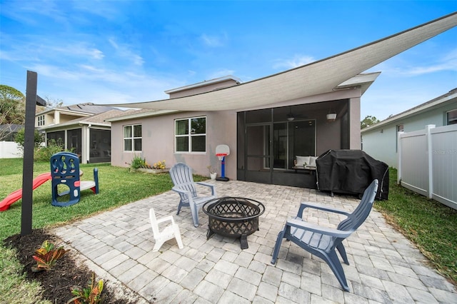 back of house featuring an outdoor fire pit, fence, a sunroom, stucco siding, and a patio area