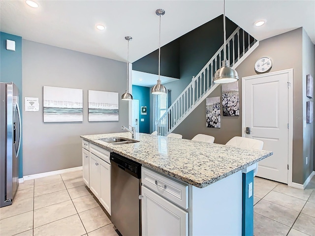 kitchen featuring sink, stainless steel appliances, white cabinets, a center island with sink, and decorative light fixtures