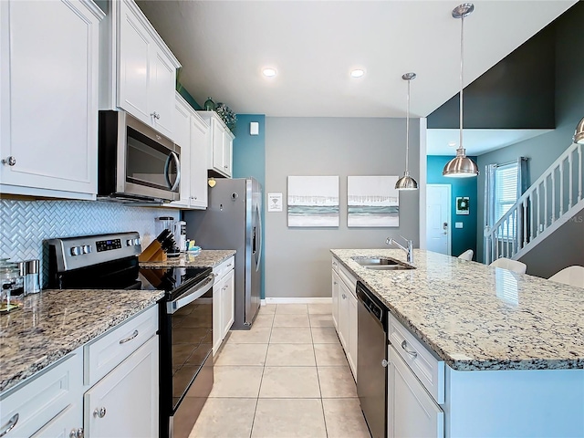 kitchen featuring sink, appliances with stainless steel finishes, an island with sink, white cabinets, and decorative light fixtures