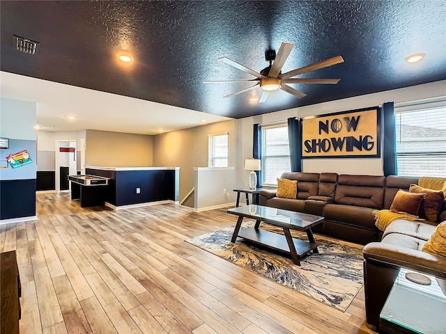 living room featuring ceiling fan, a textured ceiling, and light wood-type flooring