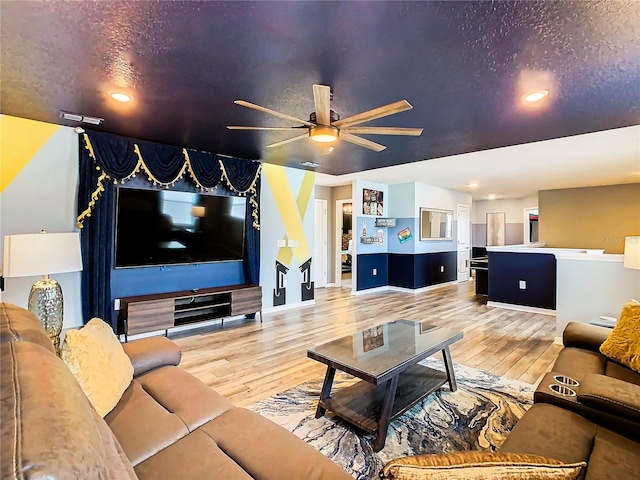 living room featuring ceiling fan, hardwood / wood-style flooring, and a textured ceiling