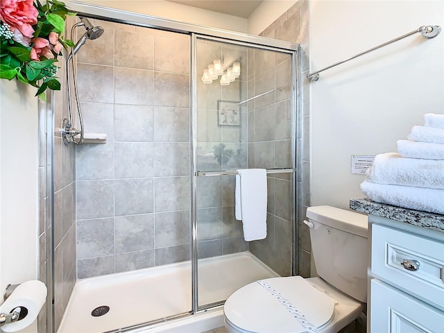 bathroom featuring toilet, vanity, and a shower with shower door