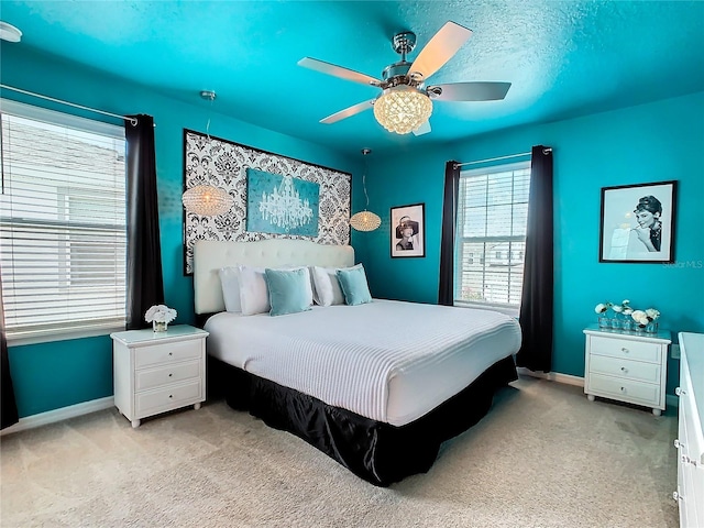 bedroom with ceiling fan, light colored carpet, and a textured ceiling