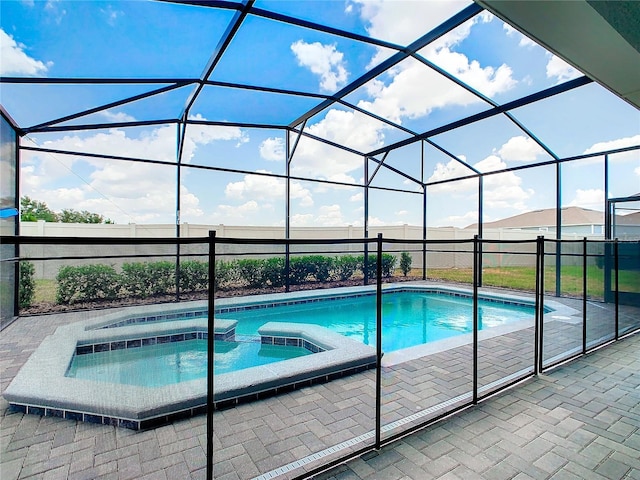 view of pool with an in ground hot tub, glass enclosure, and a patio