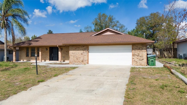 ranch-style home featuring a garage, a front lawn, and central air condition unit