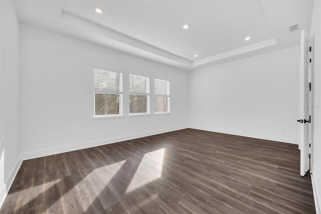 empty room with a tray ceiling and dark wood-type flooring