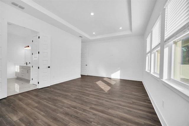 empty room featuring dark hardwood / wood-style floors and a tray ceiling