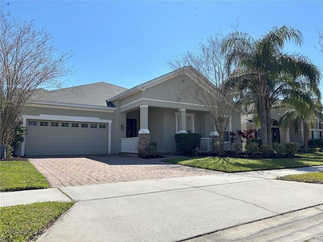 view of front of house featuring a garage, a front lawn, decorative driveway, and stucco siding