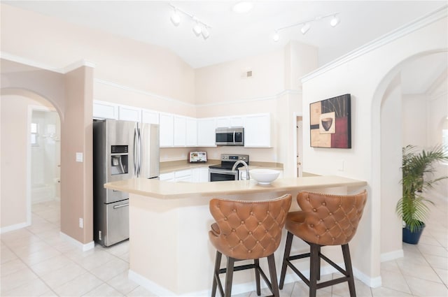 kitchen with appliances with stainless steel finishes, a kitchen breakfast bar, light tile patterned floors, and white cabinets
