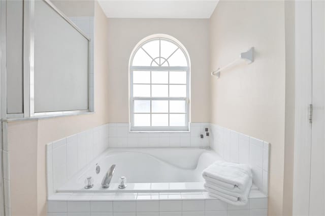 bathroom with tiled tub and a wealth of natural light