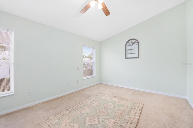 carpeted spare room featuring lofted ceiling and ceiling fan