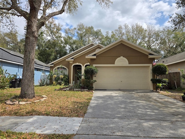 ranch-style home with an attached garage, fence, concrete driveway, and stucco siding