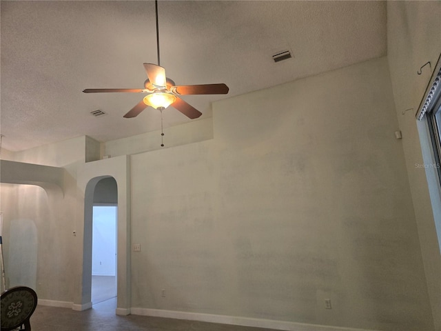 unfurnished room with arched walkways, visible vents, a textured ceiling, and baseboards