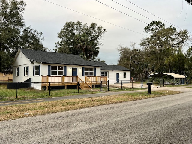 view of front of home with a carport, a deck, and a front lawn