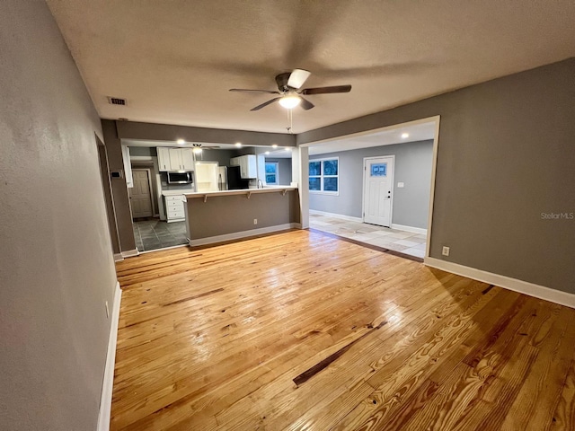 unfurnished living room featuring hardwood / wood-style floors, a textured ceiling, and ceiling fan