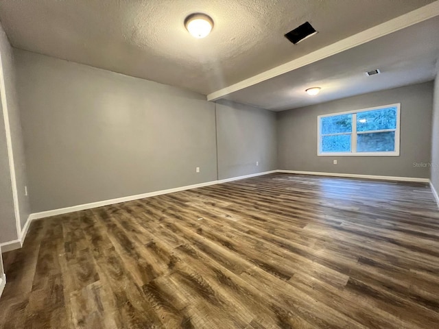 empty room featuring dark wood-type flooring and a textured ceiling