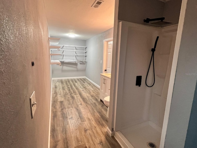 bathroom featuring vanity, hardwood / wood-style floors, toilet, and a shower