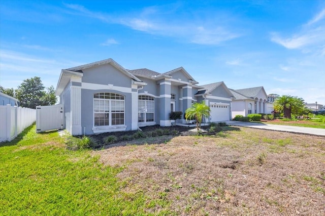 view of front of property with a garage, concrete driveway, fence, a front lawn, and stucco siding