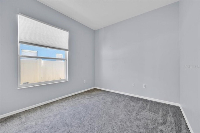 carpeted empty room featuring baseboards