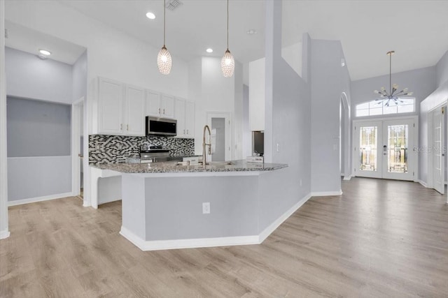 kitchen featuring stone counters, a sink, white cabinets, appliances with stainless steel finishes, and light wood finished floors