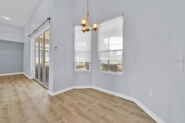 unfurnished dining area with an inviting chandelier, baseboards, and wood finished floors