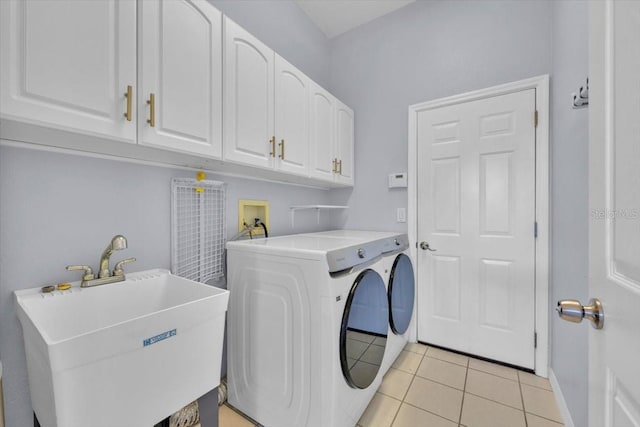 clothes washing area featuring light tile patterned floors, a sink, baseboards, washer and dryer, and cabinet space