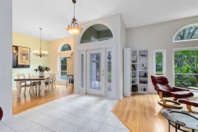 foyer featuring light wood-type flooring, an inviting chandelier, and a towering ceiling