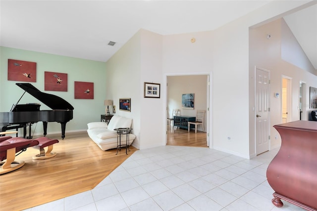 sitting room featuring high vaulted ceiling and light tile patterned floors