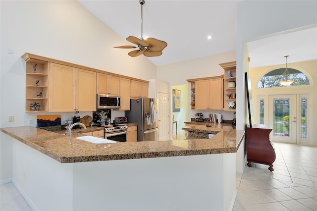 kitchen featuring light tile patterned floors, decorative light fixtures, stainless steel appliances, kitchen peninsula, and high vaulted ceiling