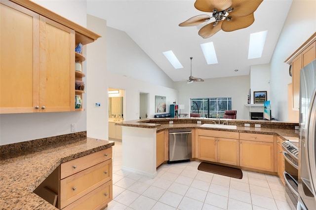 kitchen with kitchen peninsula, appliances with stainless steel finishes, light brown cabinets, and a skylight