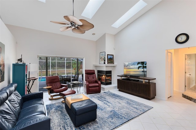 living room featuring ceiling fan, high vaulted ceiling, light tile patterned floors, and a skylight
