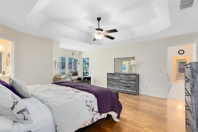 bedroom featuring light wood-type flooring, a tray ceiling, and ceiling fan