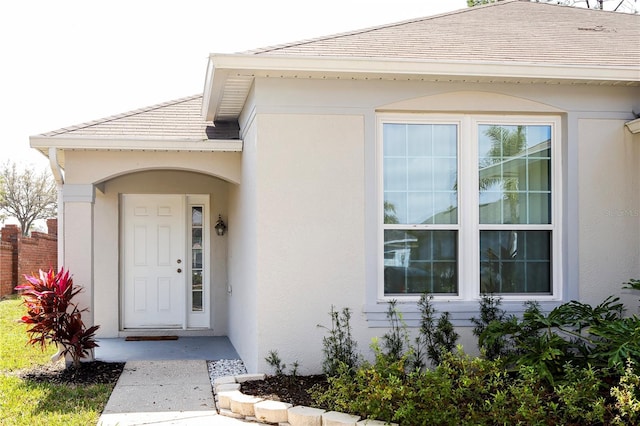 entrance to property featuring a tiled roof and stucco siding