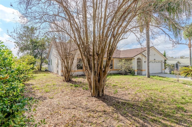 view of front of property with driveway, a front lawn, an attached garage, and stucco siding