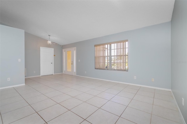 spare room with a chandelier, lofted ceiling, and baseboards