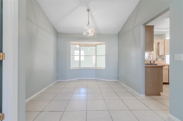 unfurnished room with baseboards, a sink, an inviting chandelier, and light tile patterned floors