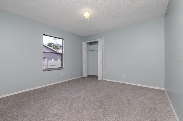 unfurnished bedroom with a closet, a textured ceiling, baseboards, and carpet flooring