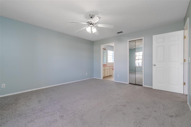 unfurnished bedroom with light carpet, a closet, a textured ceiling, and visible vents