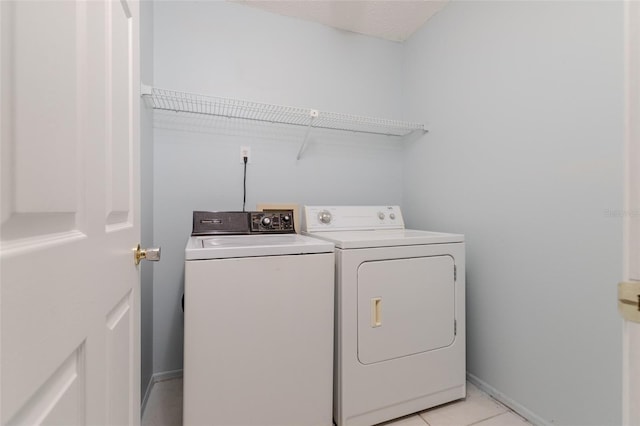 washroom with laundry area, light tile patterned floors, baseboards, and washing machine and clothes dryer