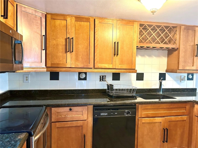 kitchen with dark stone countertops, sink, tasteful backsplash, and stainless steel appliances