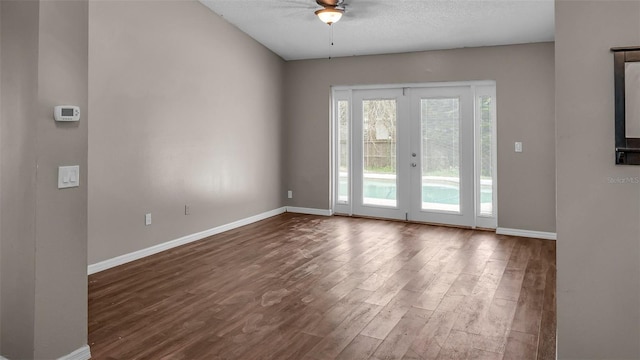 empty room featuring dark wood-style floors, french doors, a textured ceiling, and baseboards