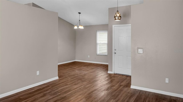 spare room featuring lofted ceiling, dark wood finished floors, and baseboards