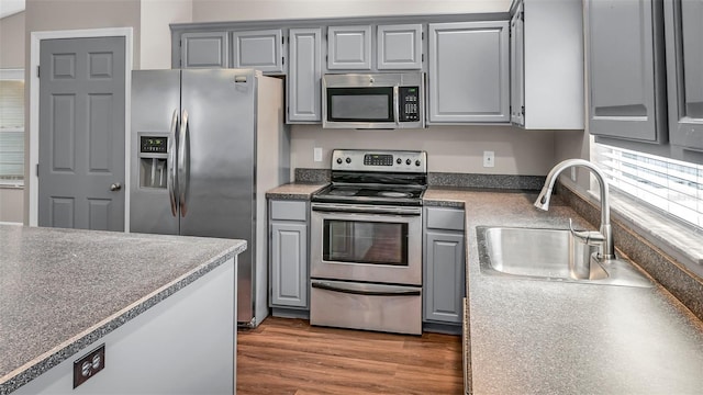 kitchen featuring dark countertops, appliances with stainless steel finishes, gray cabinets, and a sink