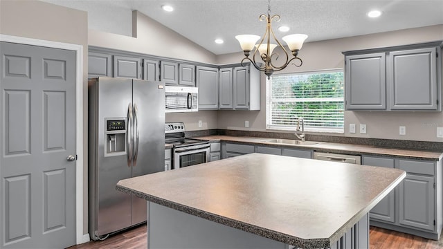 kitchen featuring lofted ceiling, stainless steel appliances, a sink, a kitchen island, and dark wood finished floors