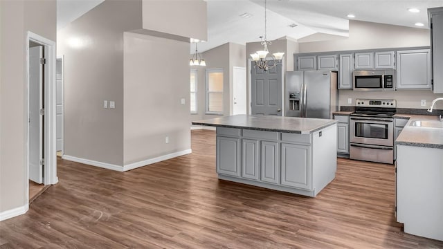 kitchen featuring gray cabinetry, stainless steel appliances, a sink, a kitchen island, and decorative light fixtures