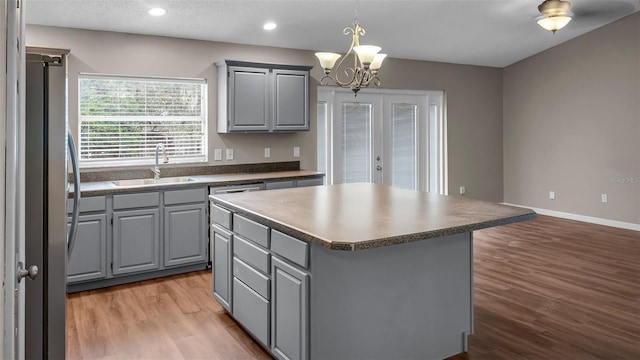 kitchen featuring a center island, gray cabinets, freestanding refrigerator, and a sink