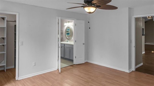 unfurnished bedroom featuring baseboards, a closet, a walk in closet, and light wood-style floors